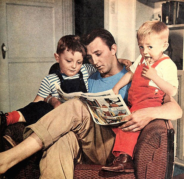  Robert Mitchum at home reading with his two sons, James Mitchum and Christopher Mitchum. | Source: Wikimedia Commons