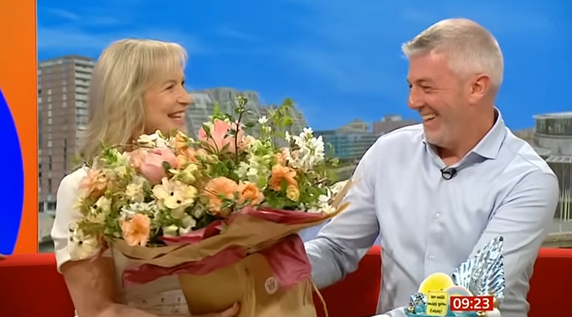 Carol Kirkwood beams as her husband, Steve Randall, surprises her with a bouquet of flowers during her final BBC Breakfast broadcast on 1 April 2026. | Source: YouTube/Weegie Bored