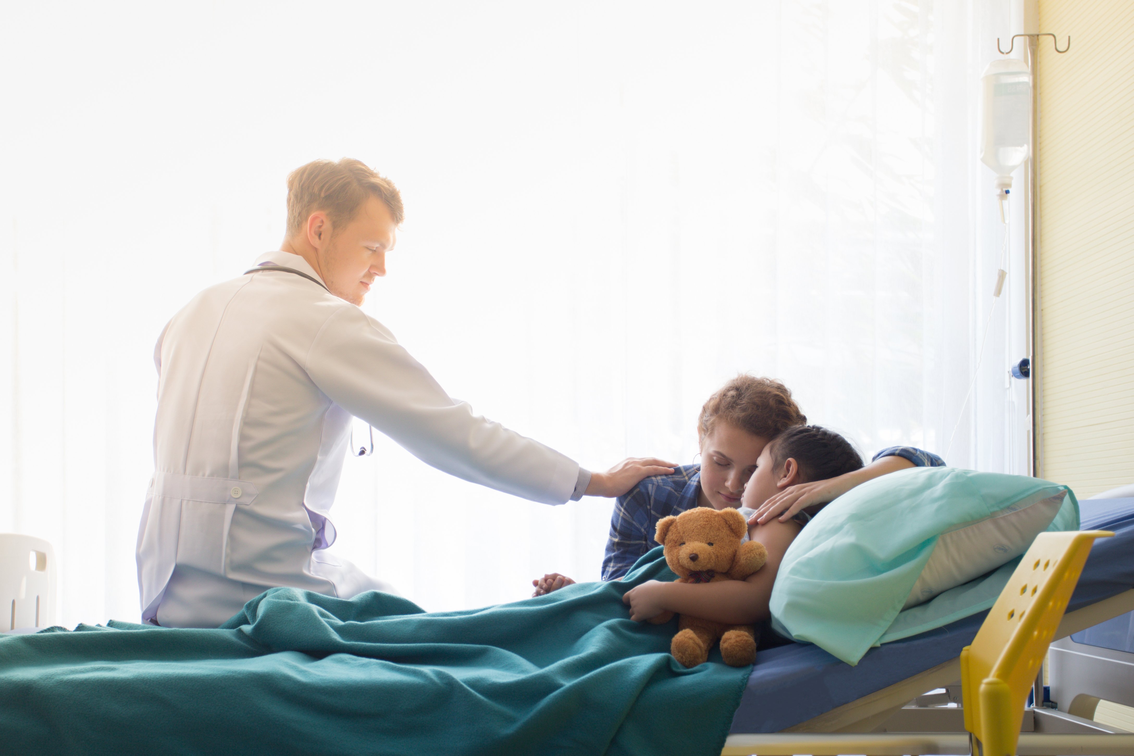 Un médecin qui rassure une mère et son enfant sur un lit d'hôpital | Photo : Shutterstock Un médecin qui rassure une mère et son enfant sur un lit d'hôpital | Photo : Shutterstock