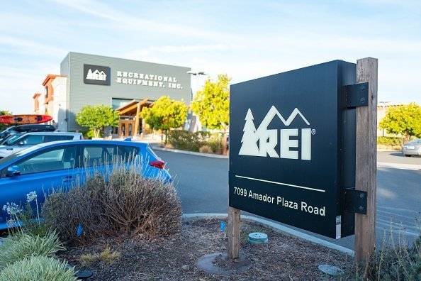 Close-up of sign for Recreational Equipment Incorporated (REI) outdoor clothing store, with facade of store in background, in Dublin, California, July 23, 2018 | Photo: Getty Images