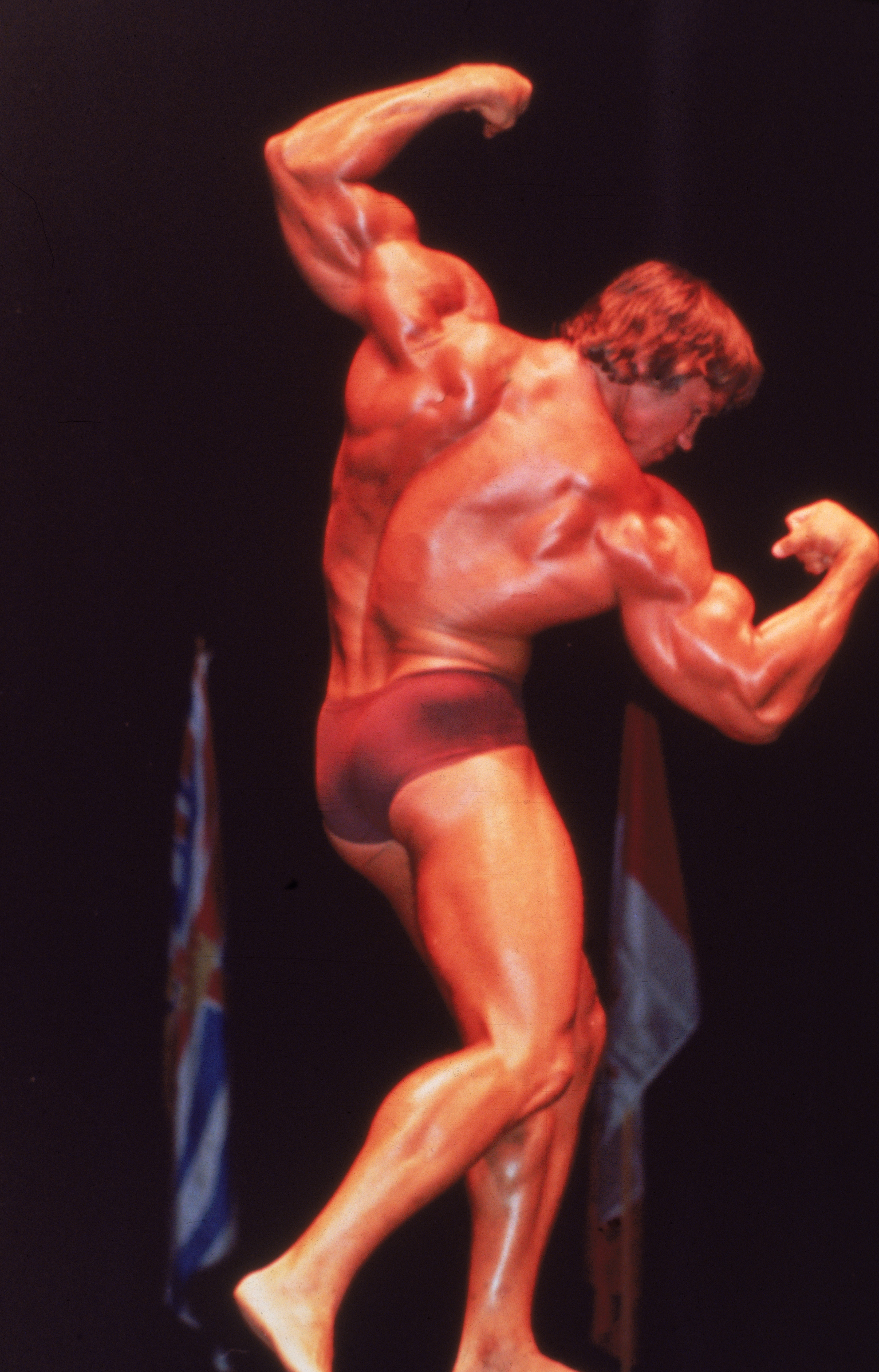 Arnold Schwarzenegger flexes his muscles onstage, circa 1970s. | Source: Getty Images