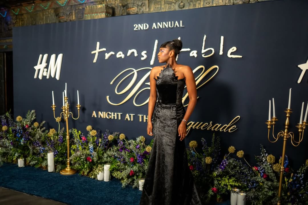Zaya Wade poses before the 2nd Annual Translatable Ball backdrop in a sculpted black gown, framed by floral displays and gold candelabras. | Source: Instagram/translatableproject