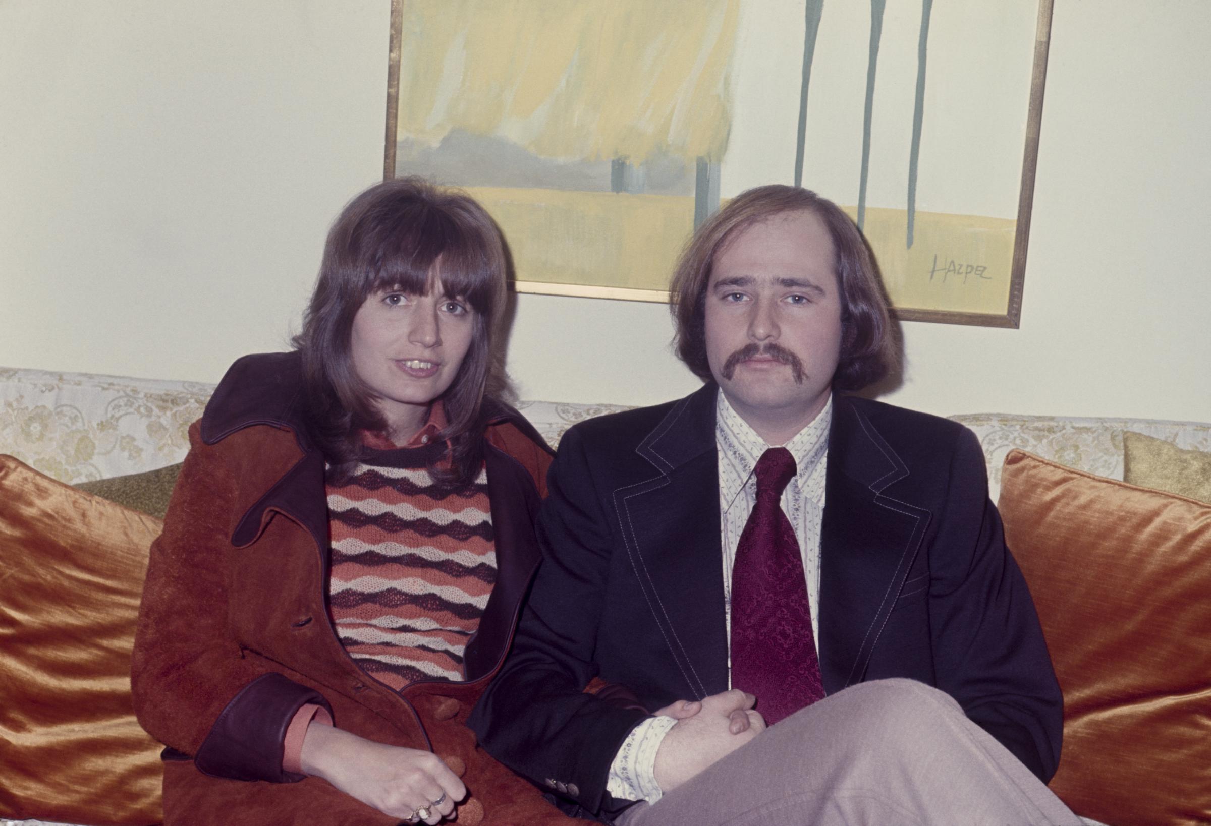 Rob Reiner with his wife Penny Marshall sitting on a sofa; circa 1970
