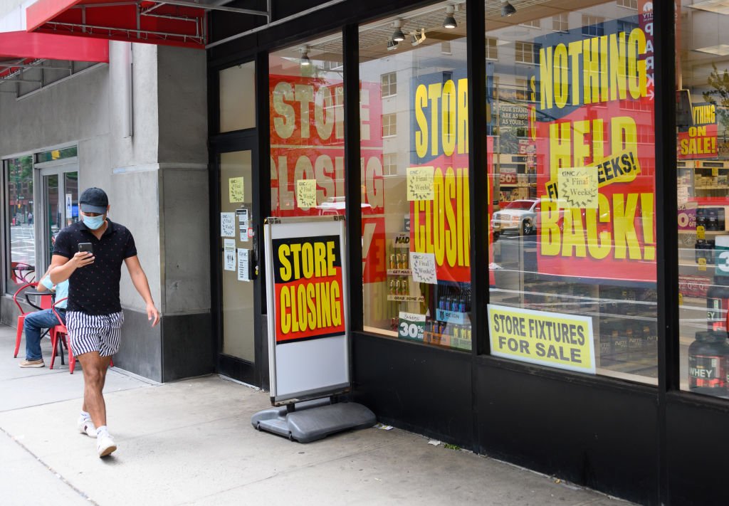 A person wears a protective face mask outside a store that puts out the "closing" sign on August 7, 2020 in New York City | Photo: Getty Images