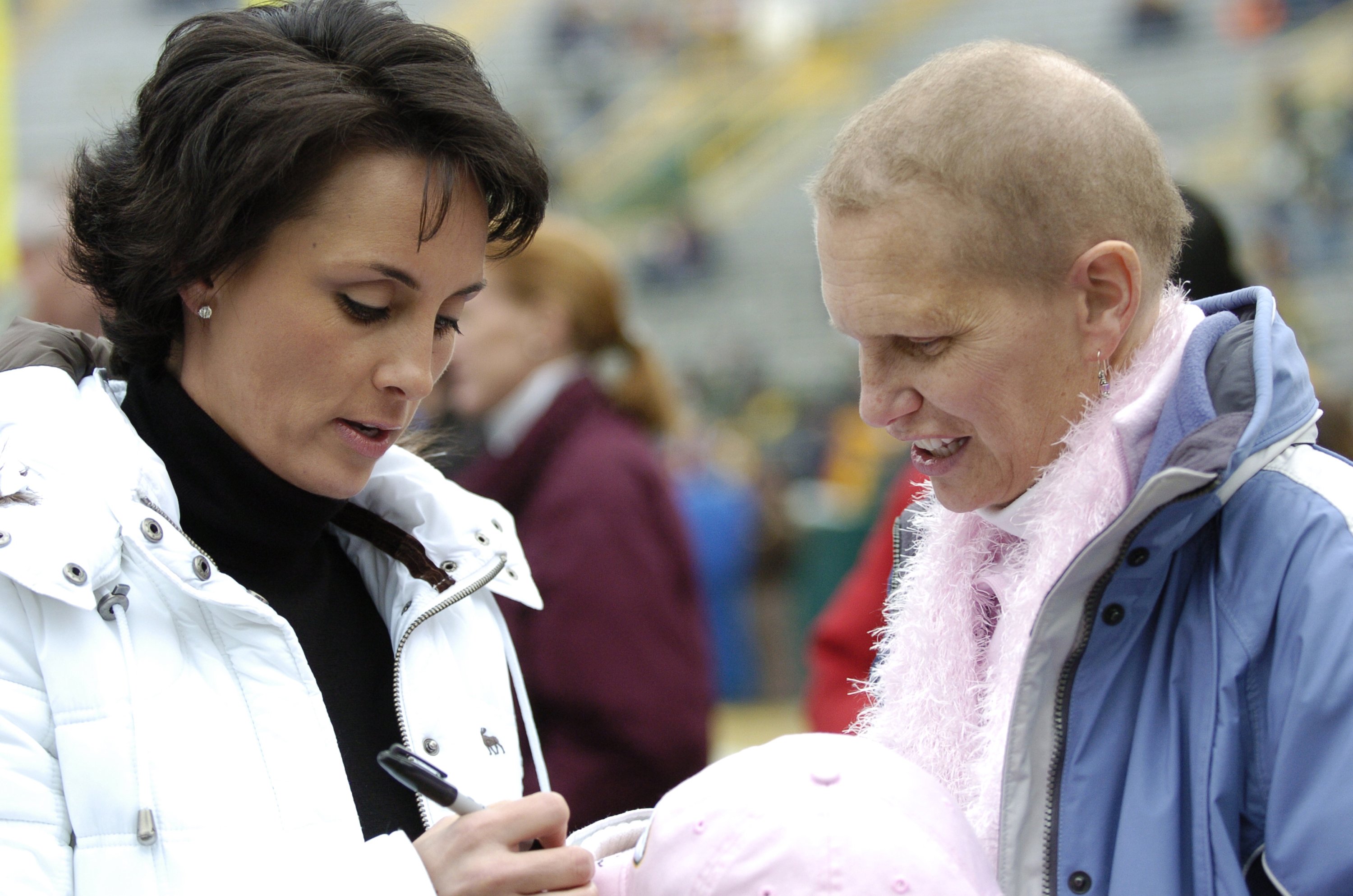 Deanna Favre signs the hat of another cancer survivor before the start of a Green Bay Packer - Seattle Seahawks game in 2006. | Source: Getty Images
