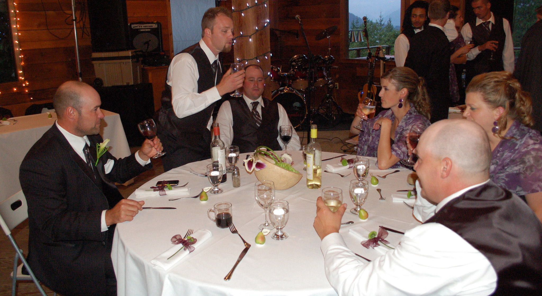 A man raising his glass at a table where other wedding guests are seated | Source: Flickr