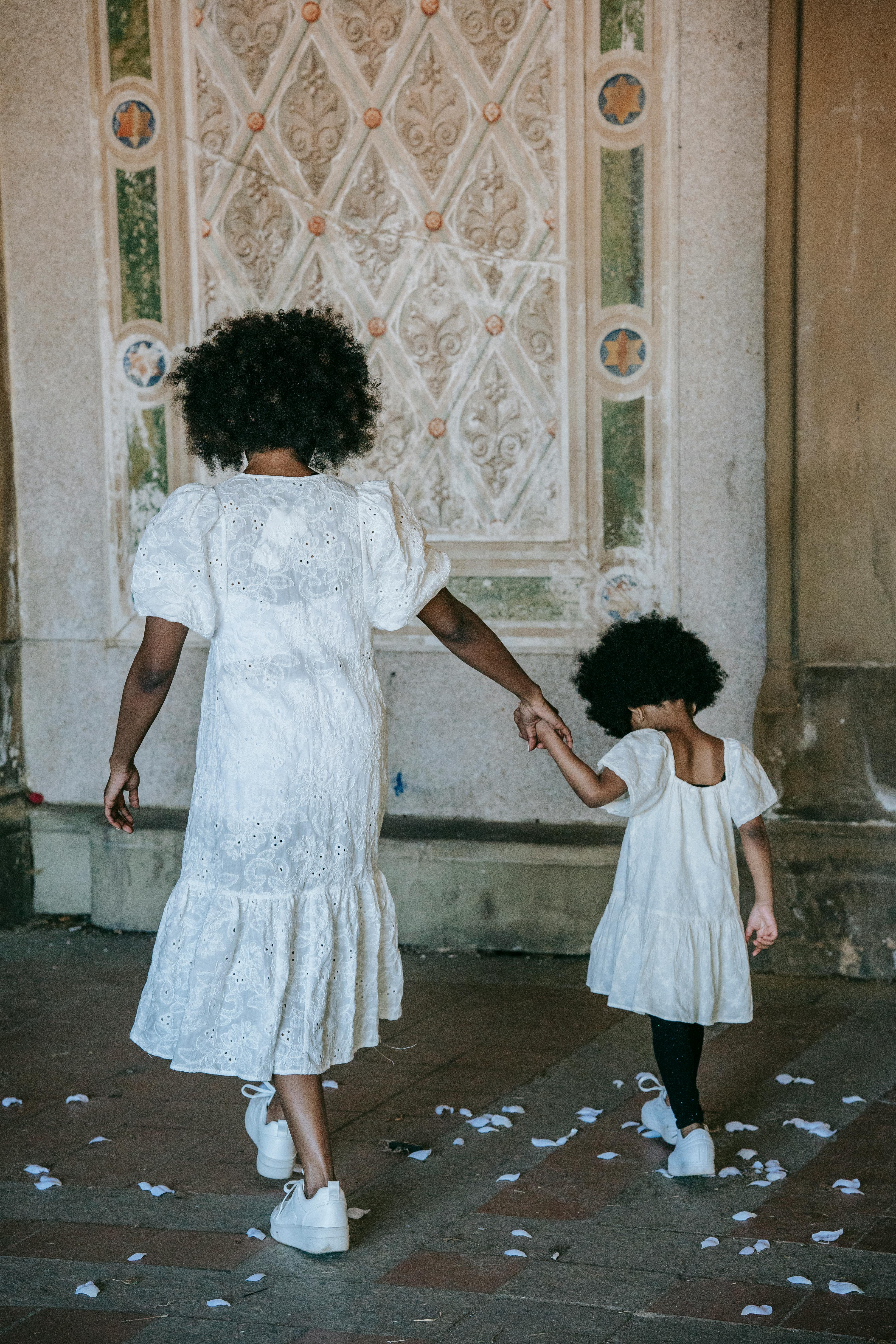 A woman and a child holding hands while walking away | Source: Pexels