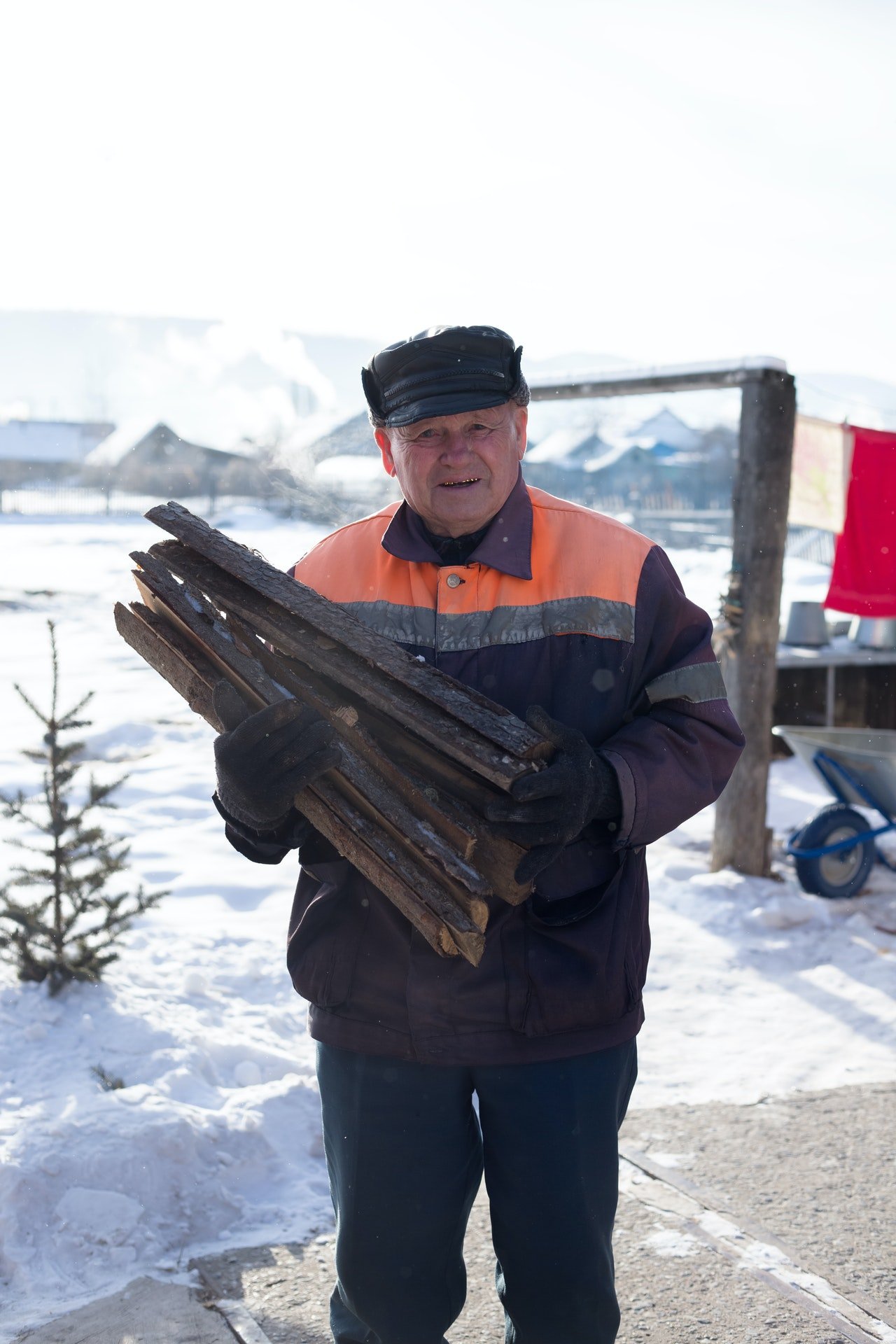 Old man carrying chopped wood | Photo: Pexels