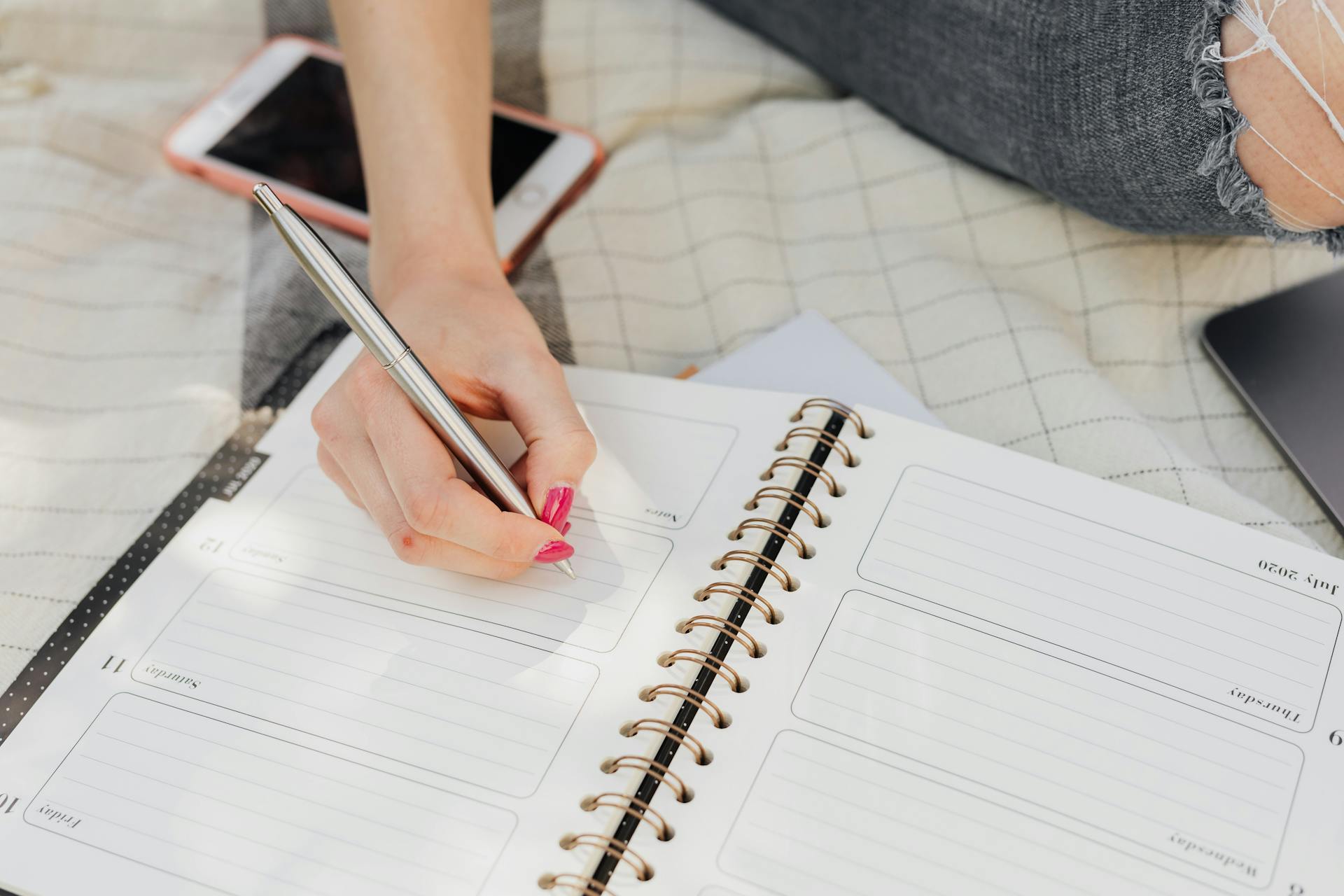 Close-up shot of a woman writing in a planner | Source: Pexels