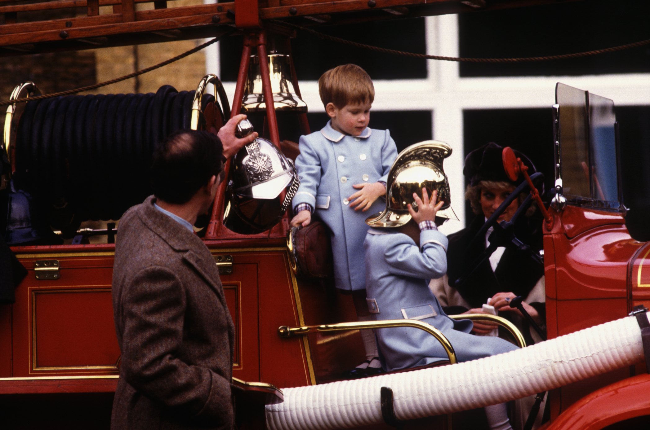 Prince Charles and his wife, Princess Diana, with their sons Prince Harry and Prince William who are pictured playing on a vintage fire engine at Sandringham. / Source: Getty Images