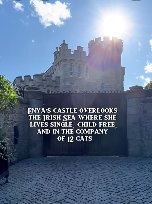 Sunlight spills over the turrets and stone battlements of Ayesha Castle, its imposing gates closed to the world beyond, as the 19th-century structure rises against a clear blue sky. The February 16, 2026, video capture offers a rare modern glimpse of the fortress-like home Enya quietly transformed into her private sanctuary overlooking the Irish Sea. | Source: YouTube/@beforethecoffin
