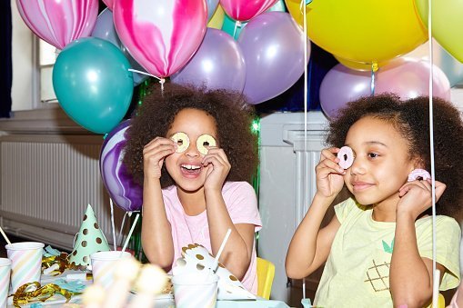 Young girl looking to camera having fun playing with food at a birthday celebration | Photo: Getty Images