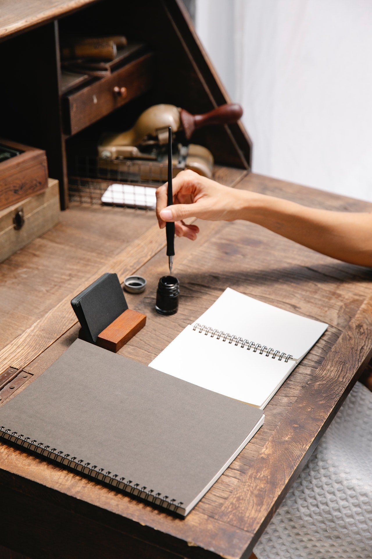 A woman dipping a pen in an inkwell | Photo: Pexels