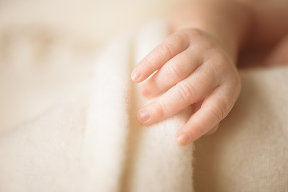 Mano de una niña recostada en una cama. | Foto: Shutterstock