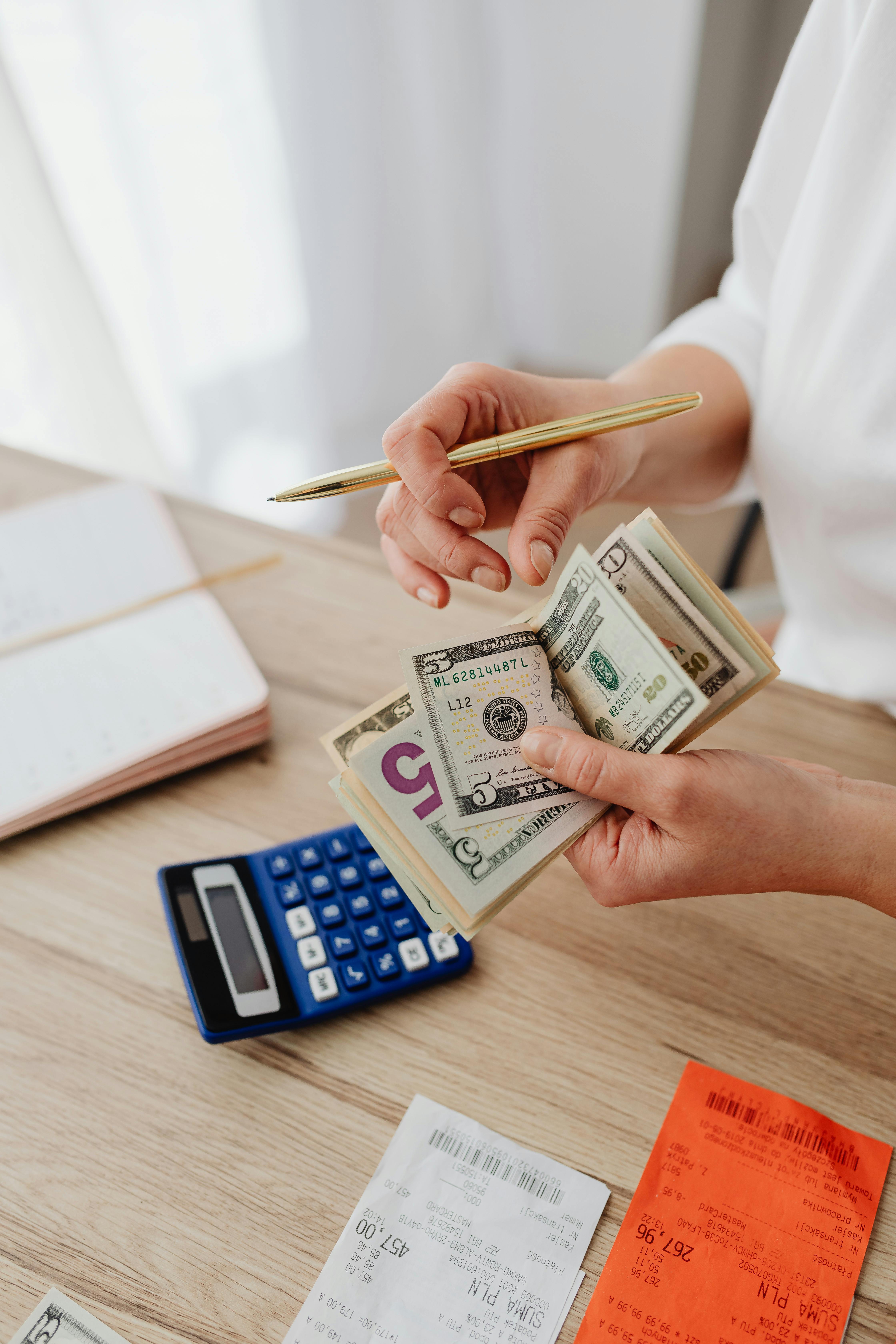 A person holding a pen and counting cash | Source: Pexels