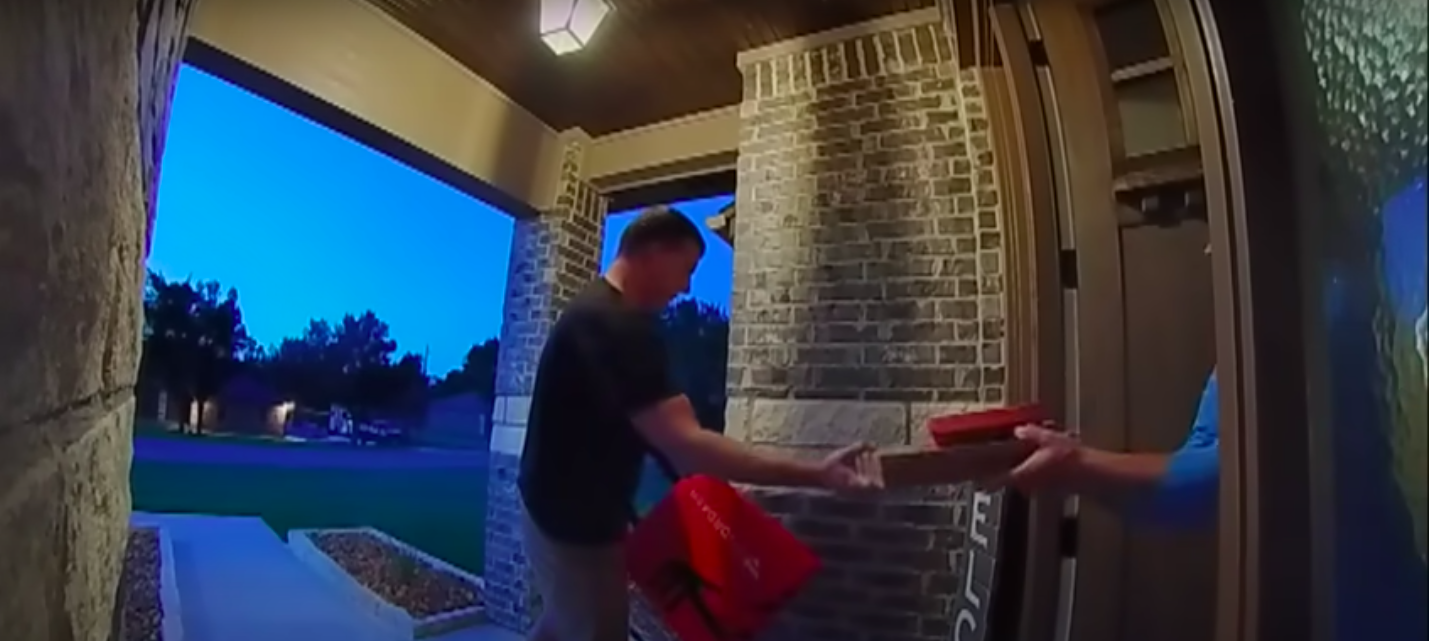 A screenshot of the DoorDash delivery man handing Lacey Purciful her pizza posted on July 5, 2023 | Source: YouTube.com/Inside Edition