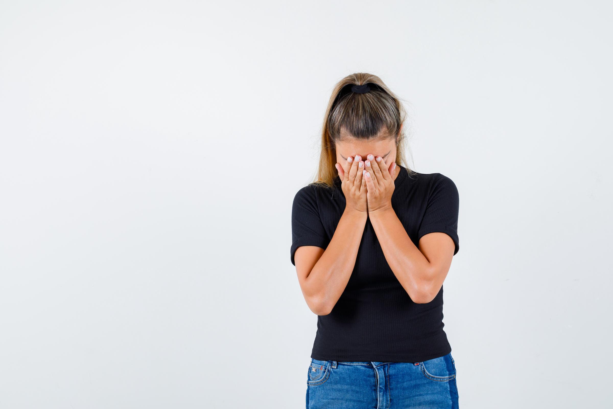 A woman hiding her face and crying | Source: Freepik