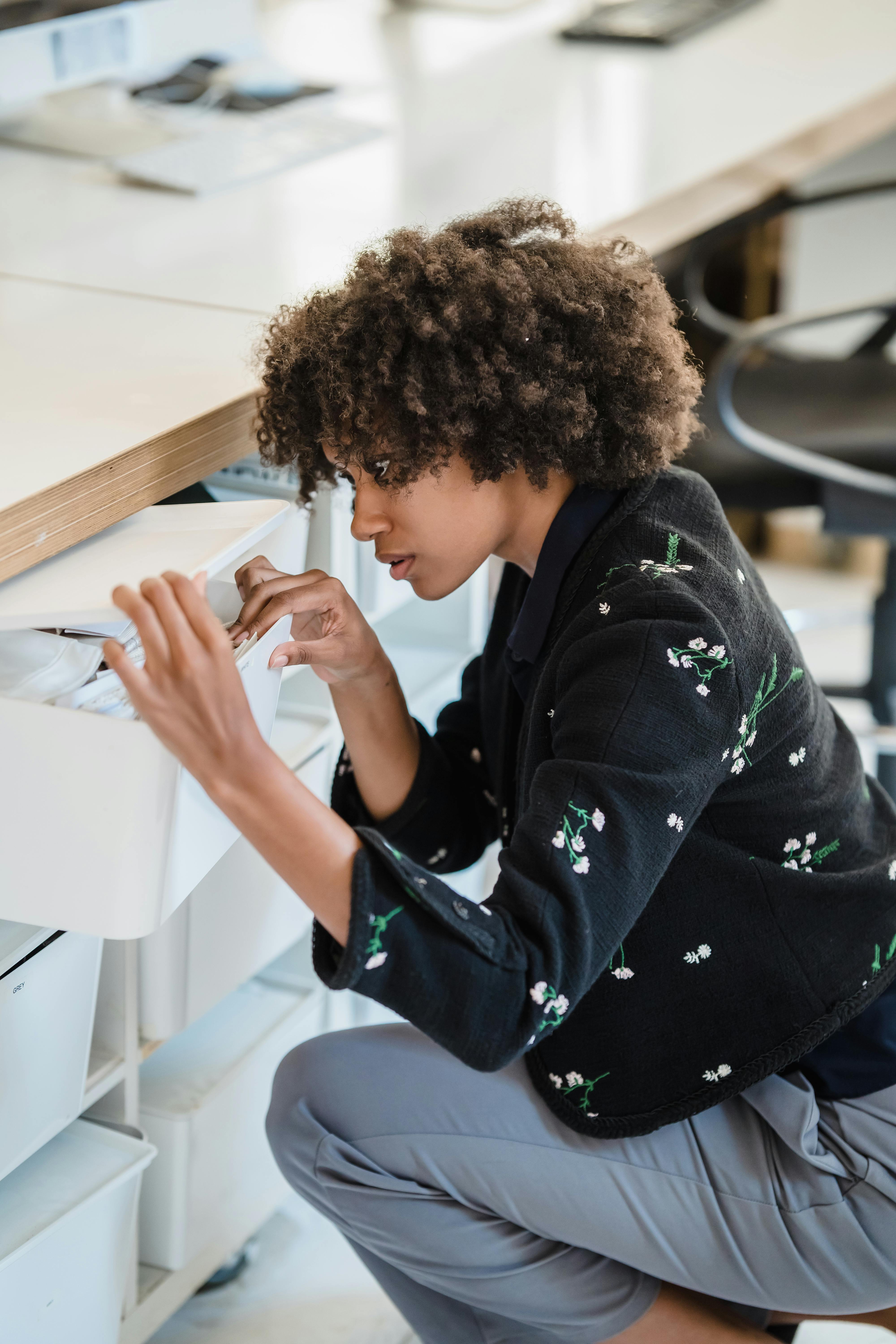 A woman searching through desk drawers | Source: Pexels