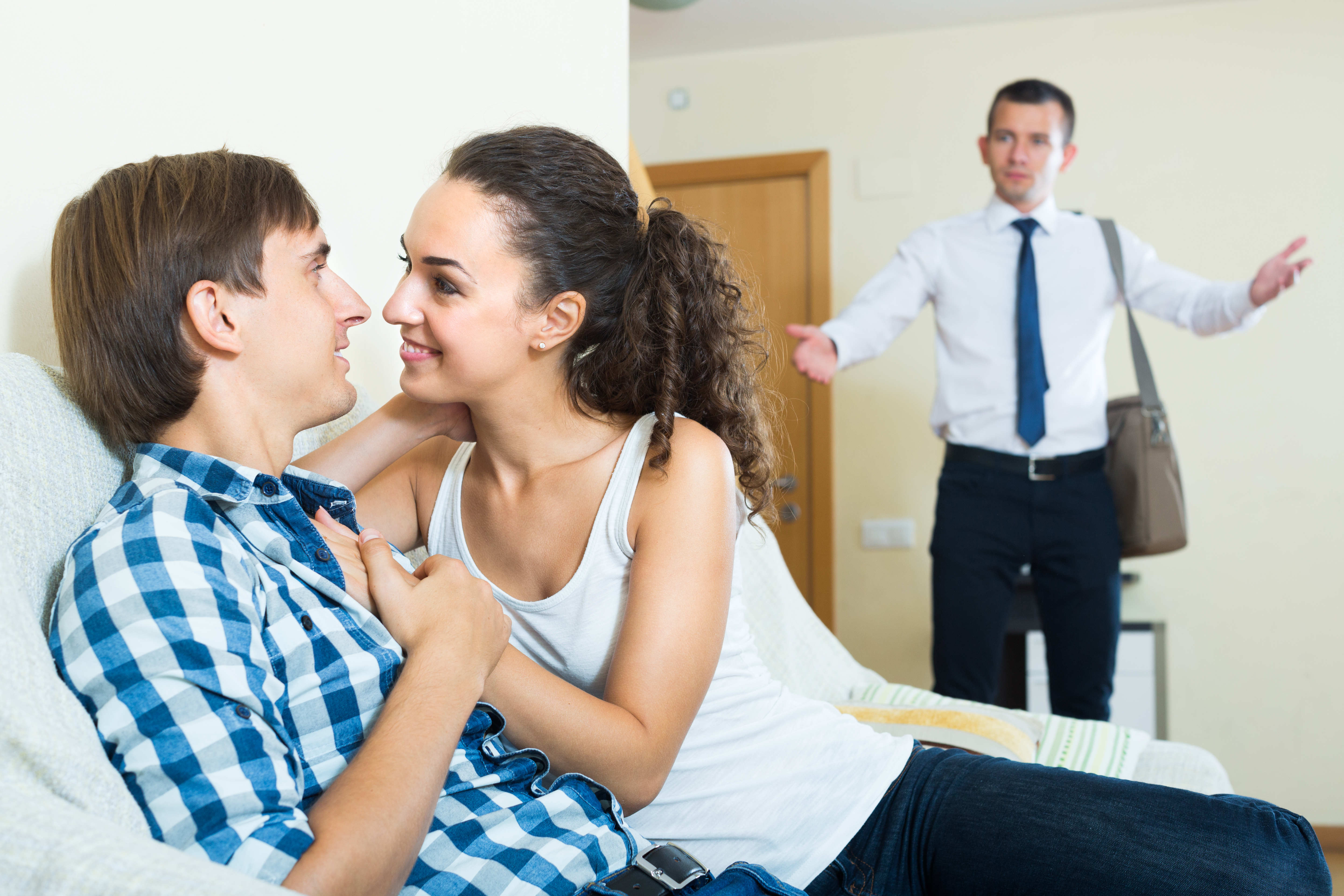 Upset man coming home and seeing girlfriend cheating on him | Source: Shutterstock