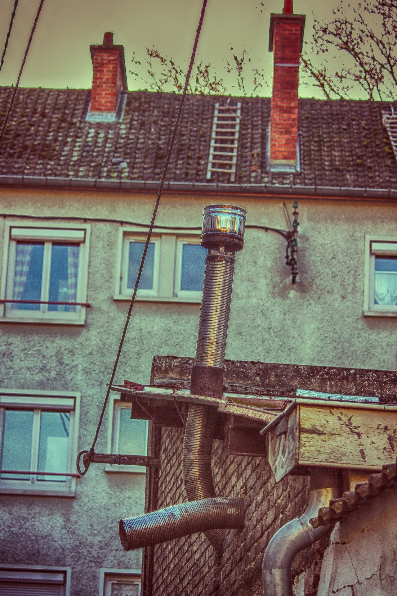 Un immeuble avec une cheminée et un tuyaux d'évacuation | Photo : Pixabay