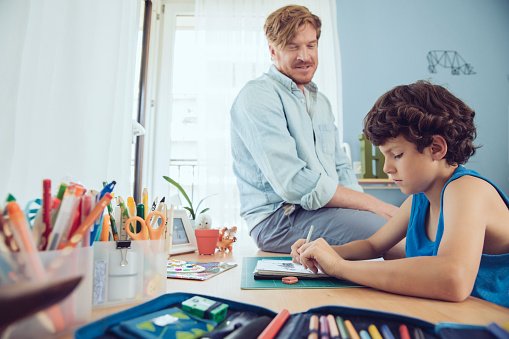 Photo of father helping boy doing his schoolwork at home | Photo: Getty Images