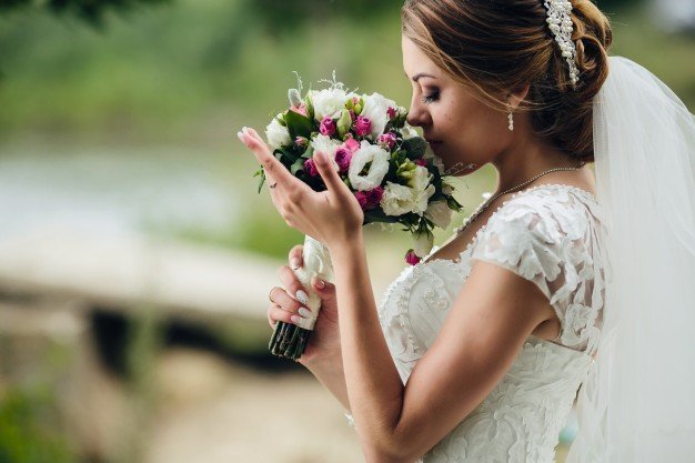Bride enjoying the scent of her bouquet. | Photo: Freepik