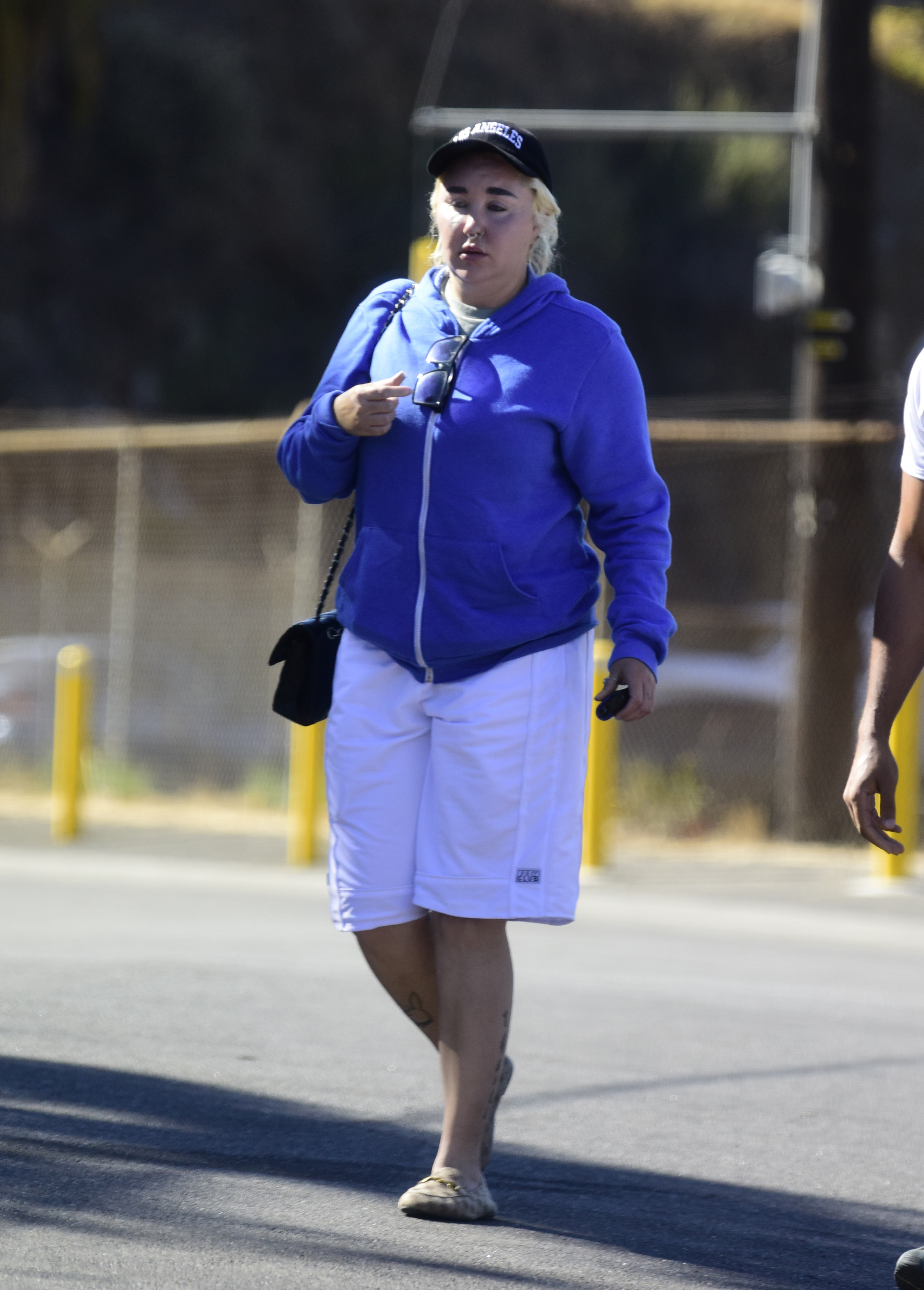 Out and about in L.A., Amanda Bynes keeps it comfortable in a blue hoodie and white shorts, carrying a crossbody bag and wearing a cap — effortlessly relaxed while on the move.