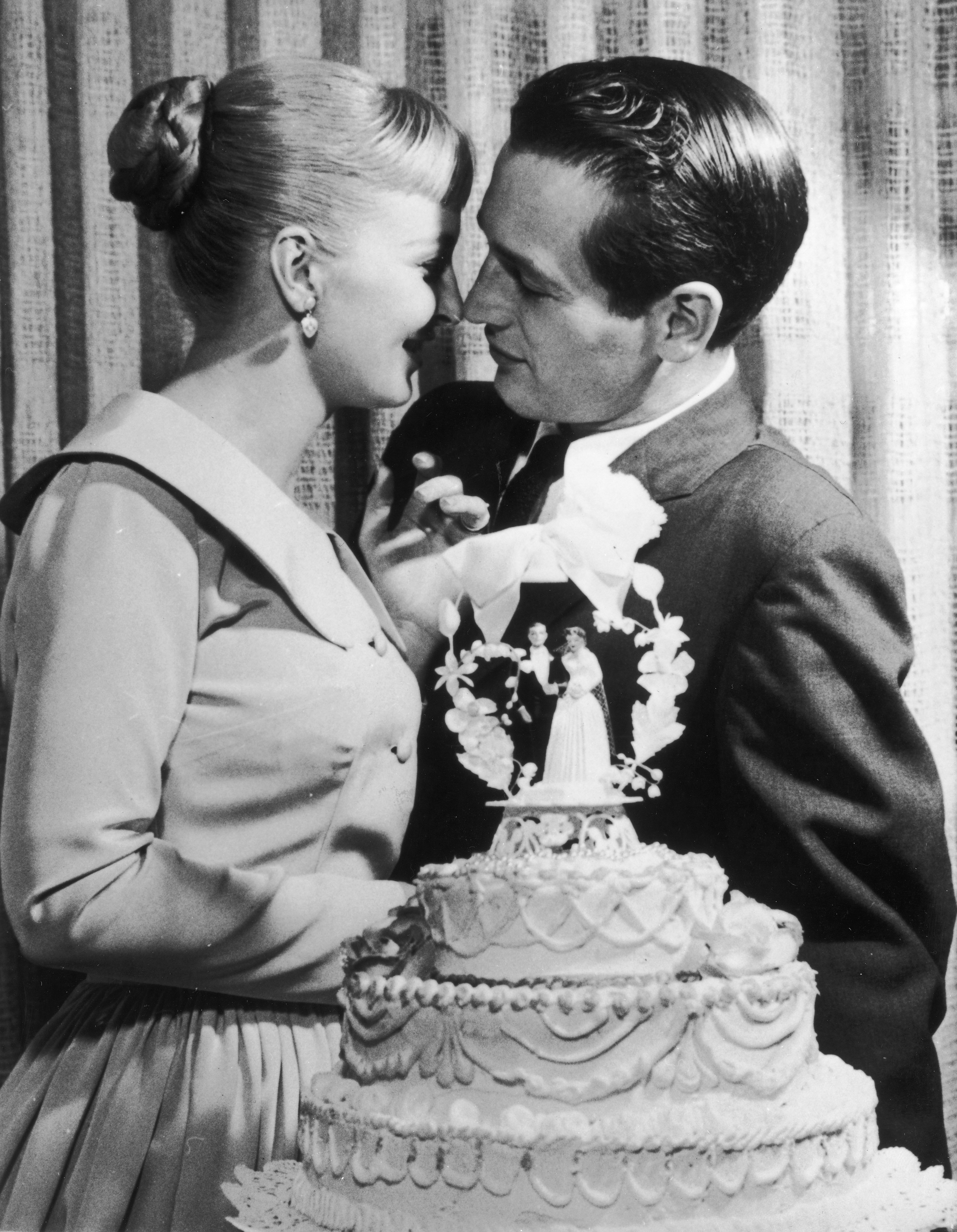 Paul Newman et Joanne Woodward s'embrassent derrière un gâteau lors de leur réception de mariage le 29 janvier 1958 à l'hôtel-casino El Rancho, à Las Vegas, Nevada. | Photo : Getty Images