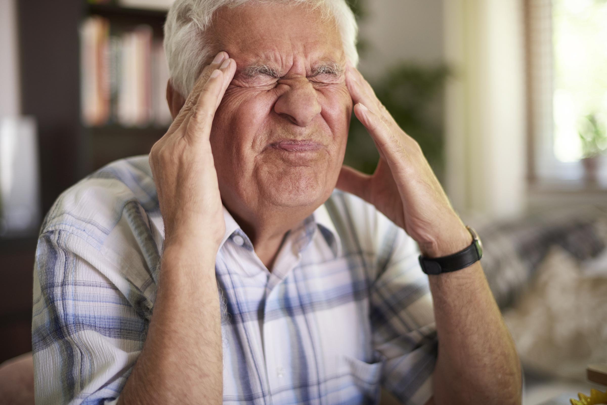 An angry older man holding his head | Source: Freepik