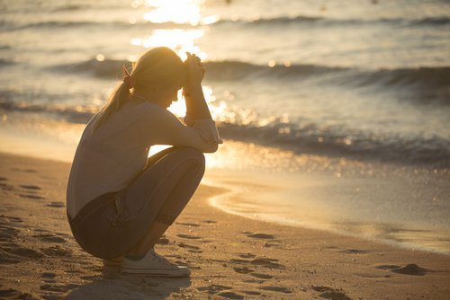 A worried young woman sitting by the water's edge. | Source: Shutterstock.