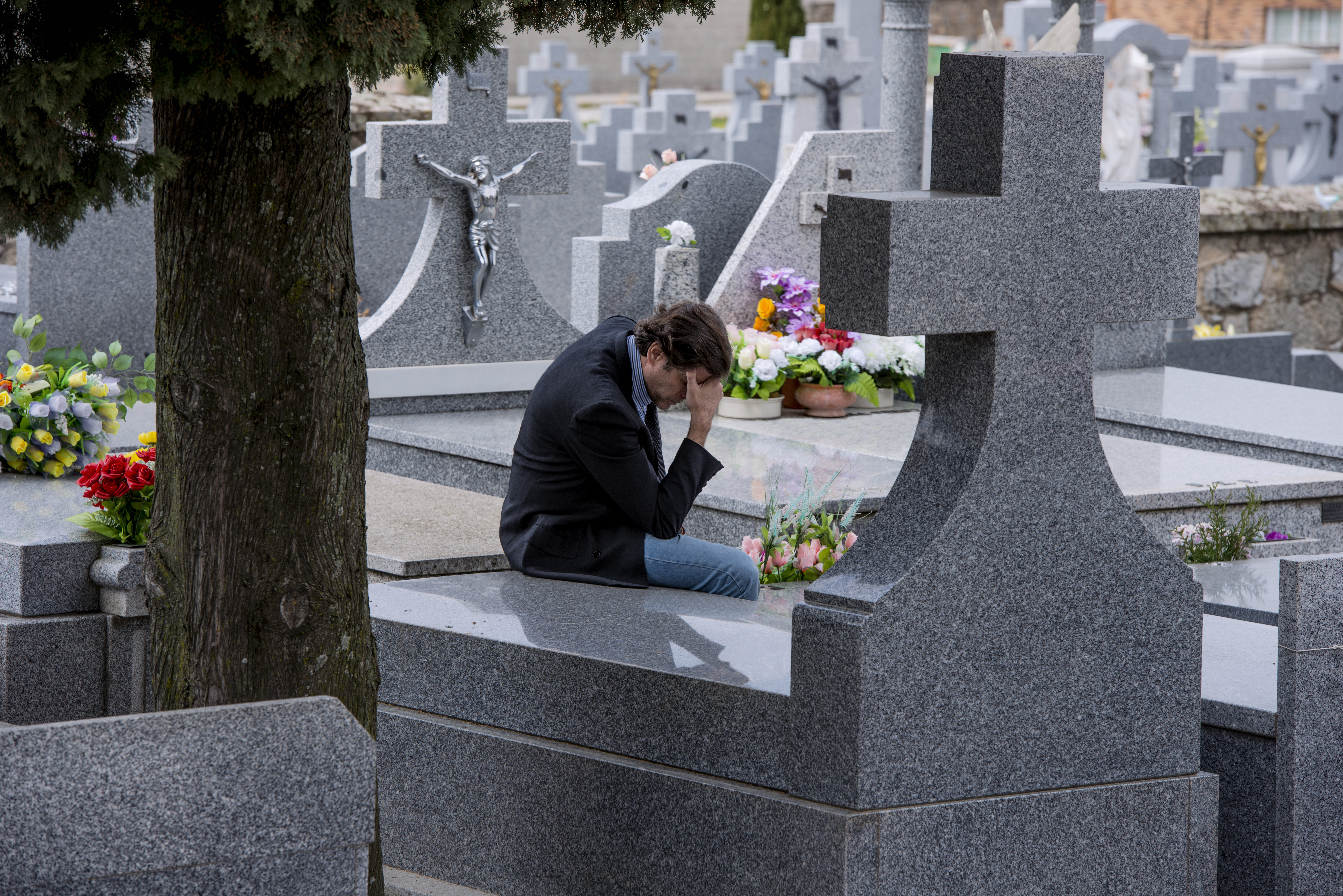 A man sitting in front of a grave | Source: Shutterstock