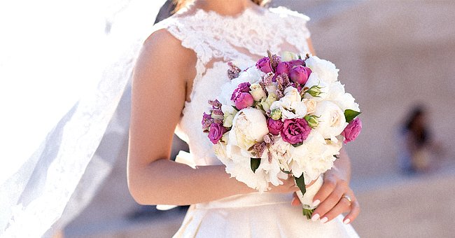 A bride dressed in her white dress holds a bouquet of flowers | Photo: Shutterstock