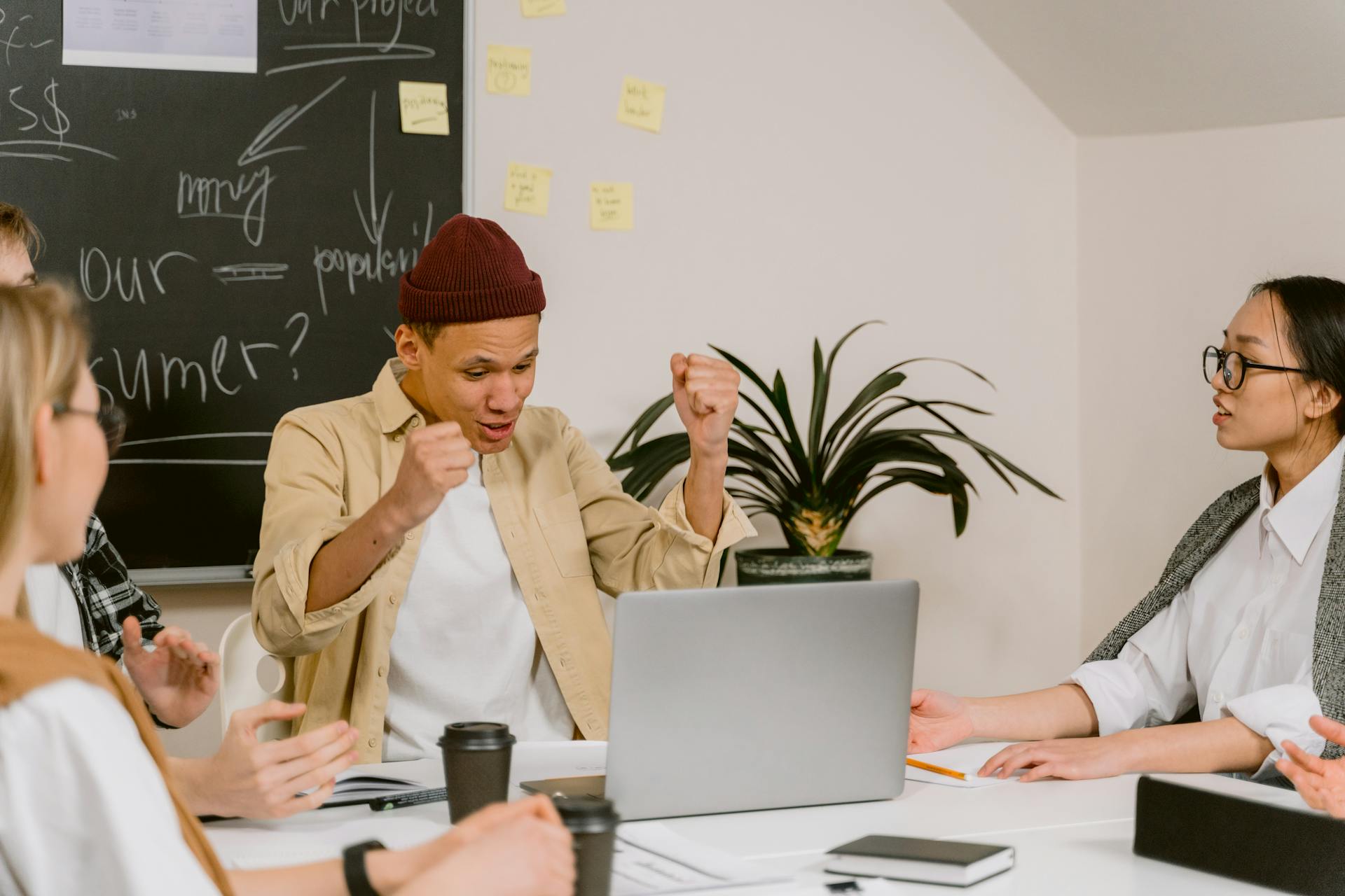 A man celebrating something while looking at his laptop screen during a work meeting | Source: Pexels