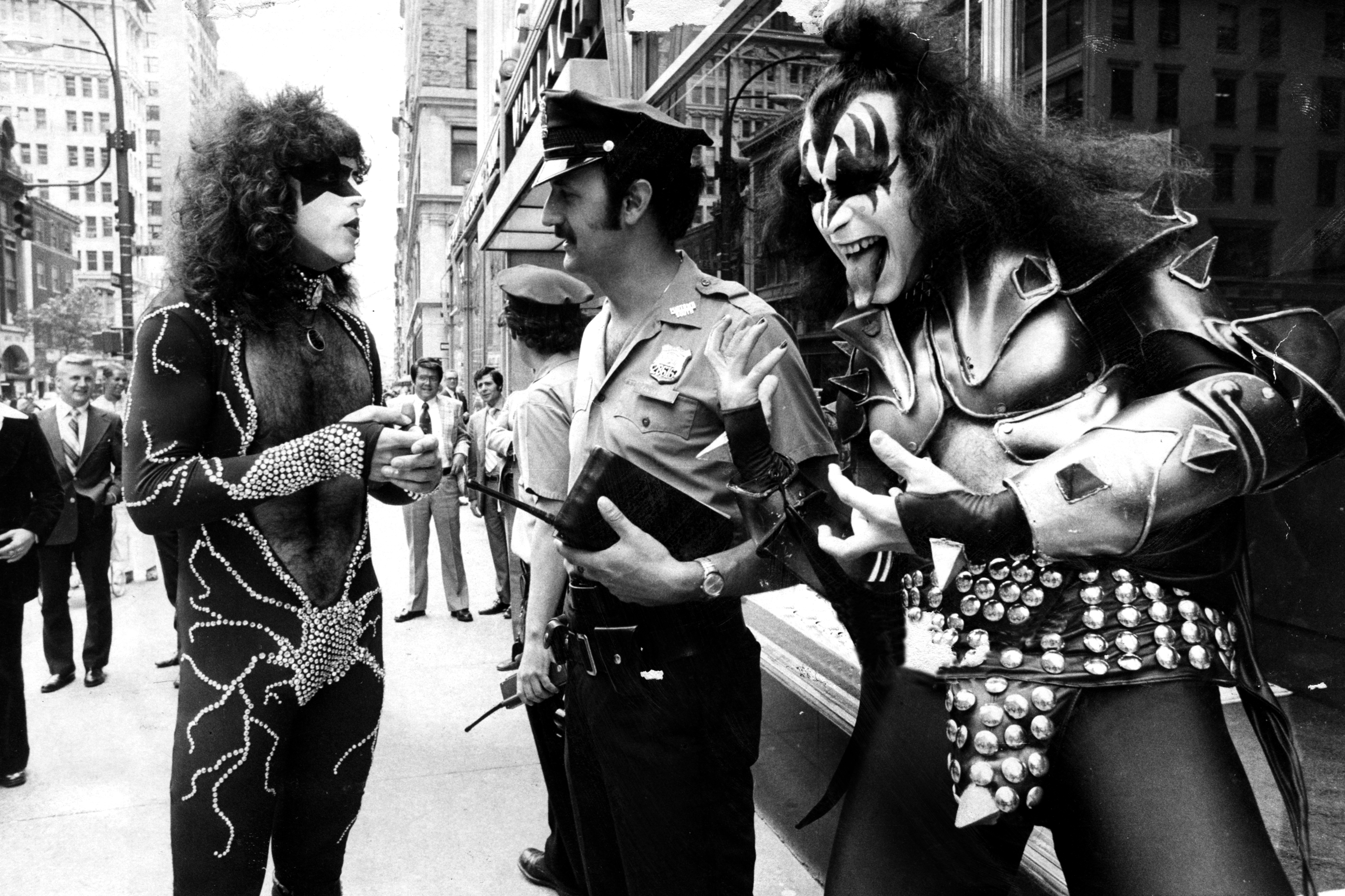 Paul Stanley and Gene Simmons of KISS photographed engaging with a police officer, circa 1976. | Source: Getty Images