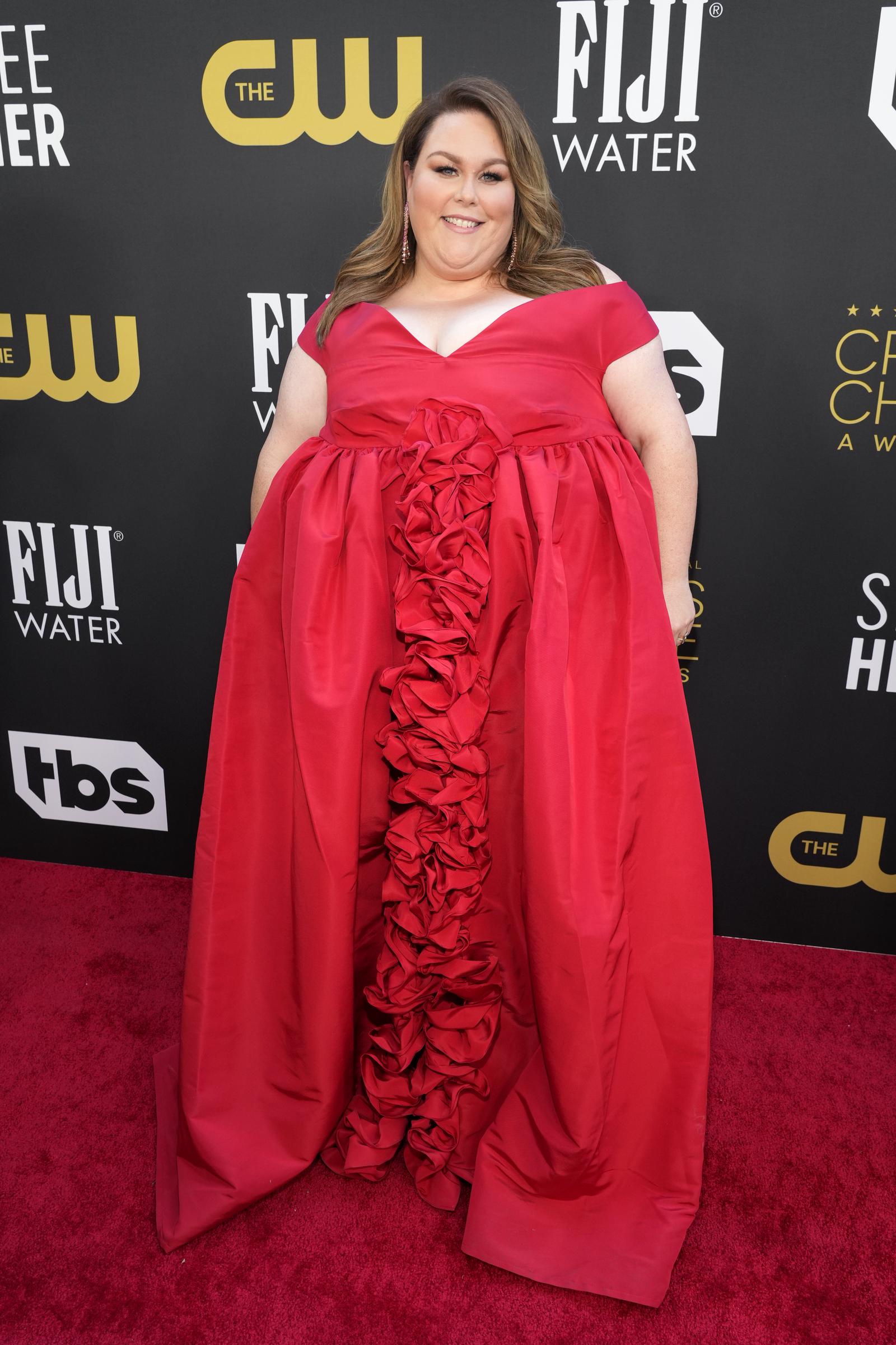 At the Critics Choice Awards, Metz wore a bright red gown with a ruffled center detail. The image offers a strong visual comparison with the more recent photos from 2025 and 2026.