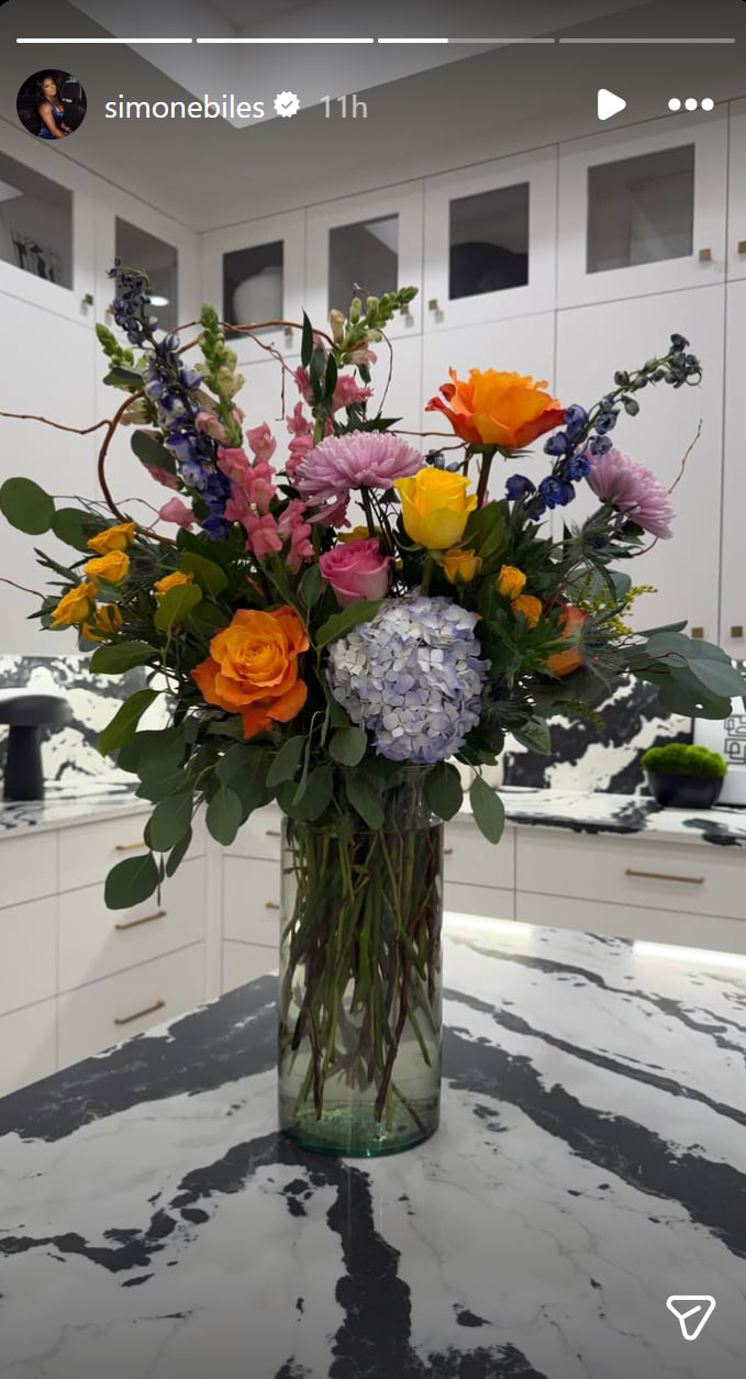 A colorful bouquet featuring roses, hydrangeas, and seasonal blooms sits on Simone Biles' kitchen island, one of several floral arrangements she received following a recent health scare. | Source: Instagram/simonebiles