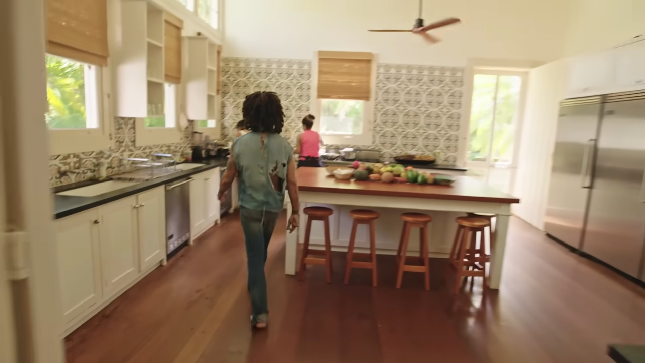Lenny walks through the bright, spacious farm kitchen, which features clean white cabinetry, traditional patterned tile backsplashes, and rich hardwood floors. | Source: YouTube/@Archdigest