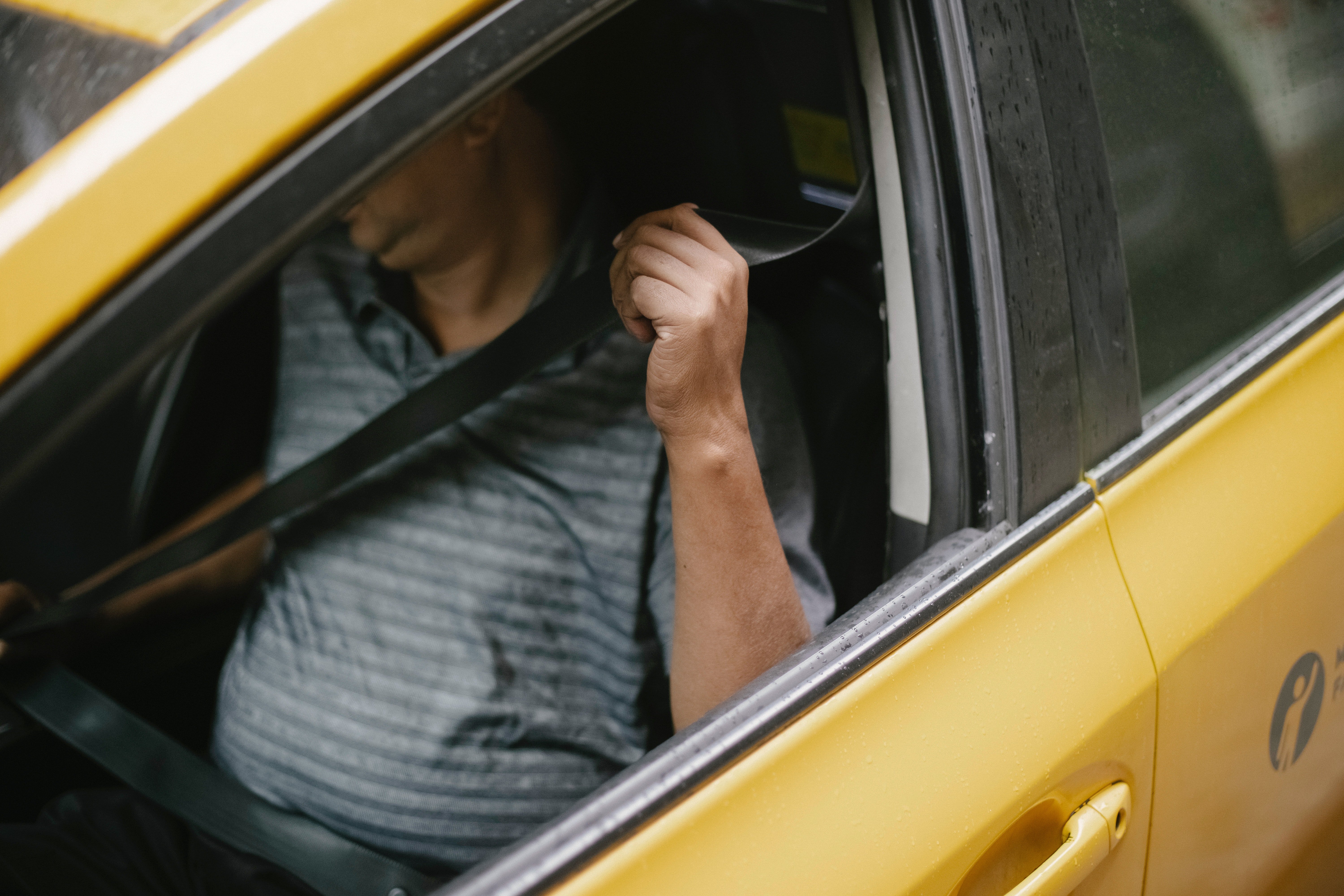 A taxi driver putting on his seatbelt | Source: Pexels