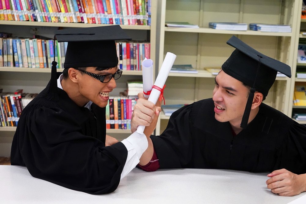 Two law graduates with gown happy in the library. | Photo: Shutterstock