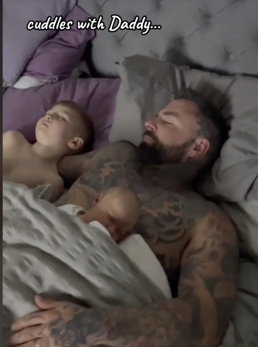 Roman is pictured sleeping with his dad, Tom, and his younger sibling. | Source: tiktok.com/@tom_leeds