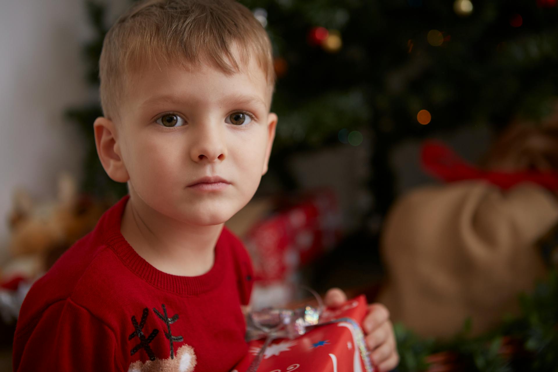 A boy looking confused with a Christmas present | Source: Pexels