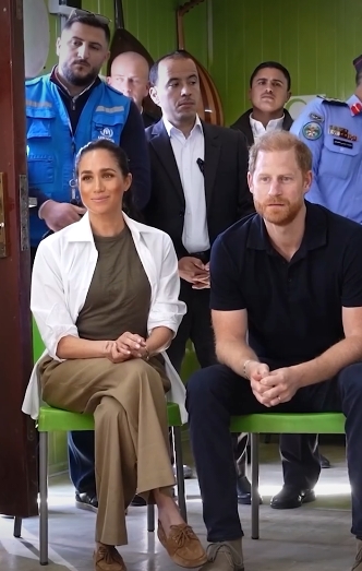 Meghan Markle and Prince Harry, Duke of Sussex, are pictured seated side by side during their visit to Jordan in a post dated February 26, 2026. The Duchess, dressed in muted earth tones, clasps her hands neatly in her lap, while the Duke leans forward with a focused expression as they listen to local officials during an engagement centred on humanitarian health and refugee support. | Source: Instagram/pagesix
