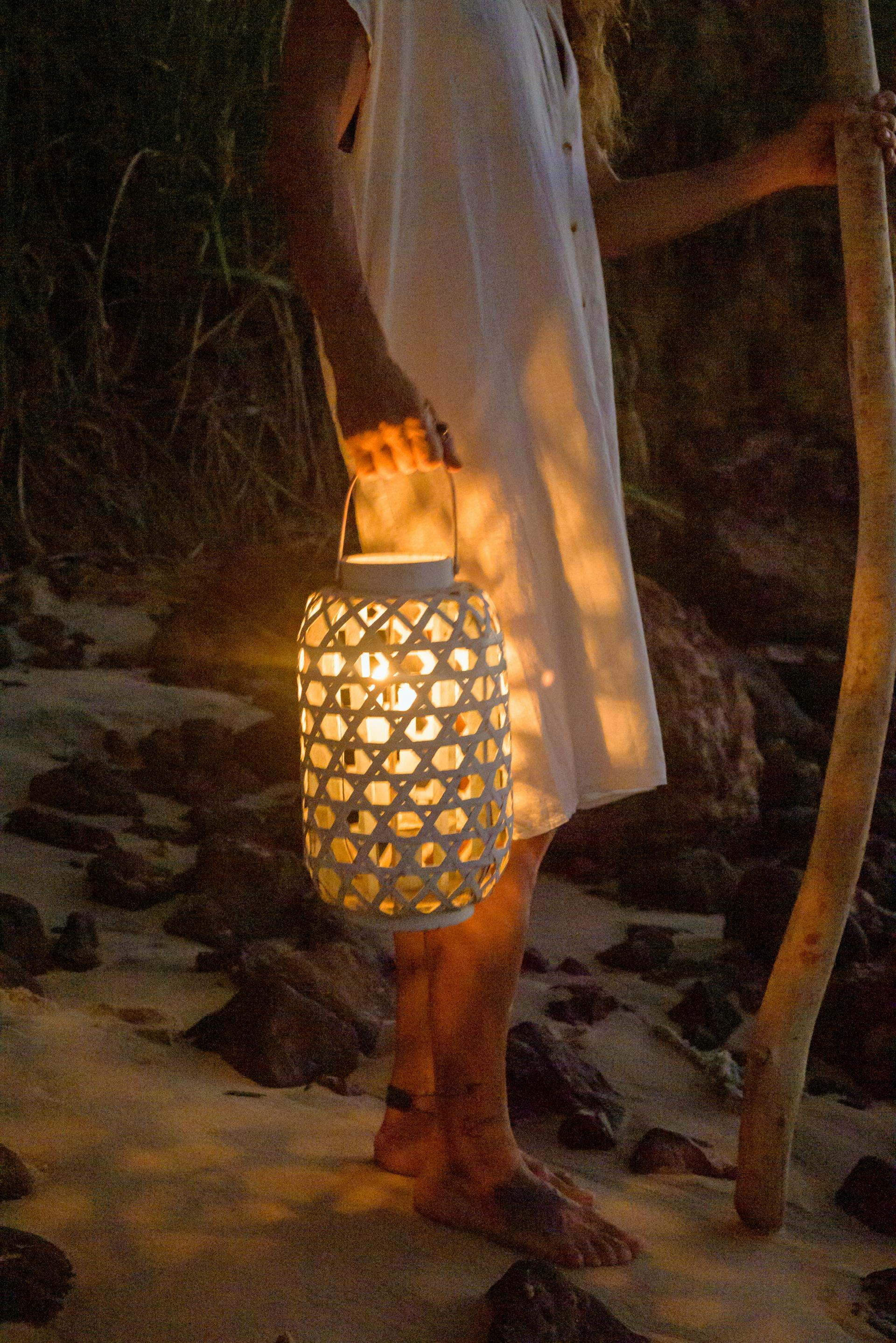 A woman standing on the beach holding a lantern | Source: Pexels