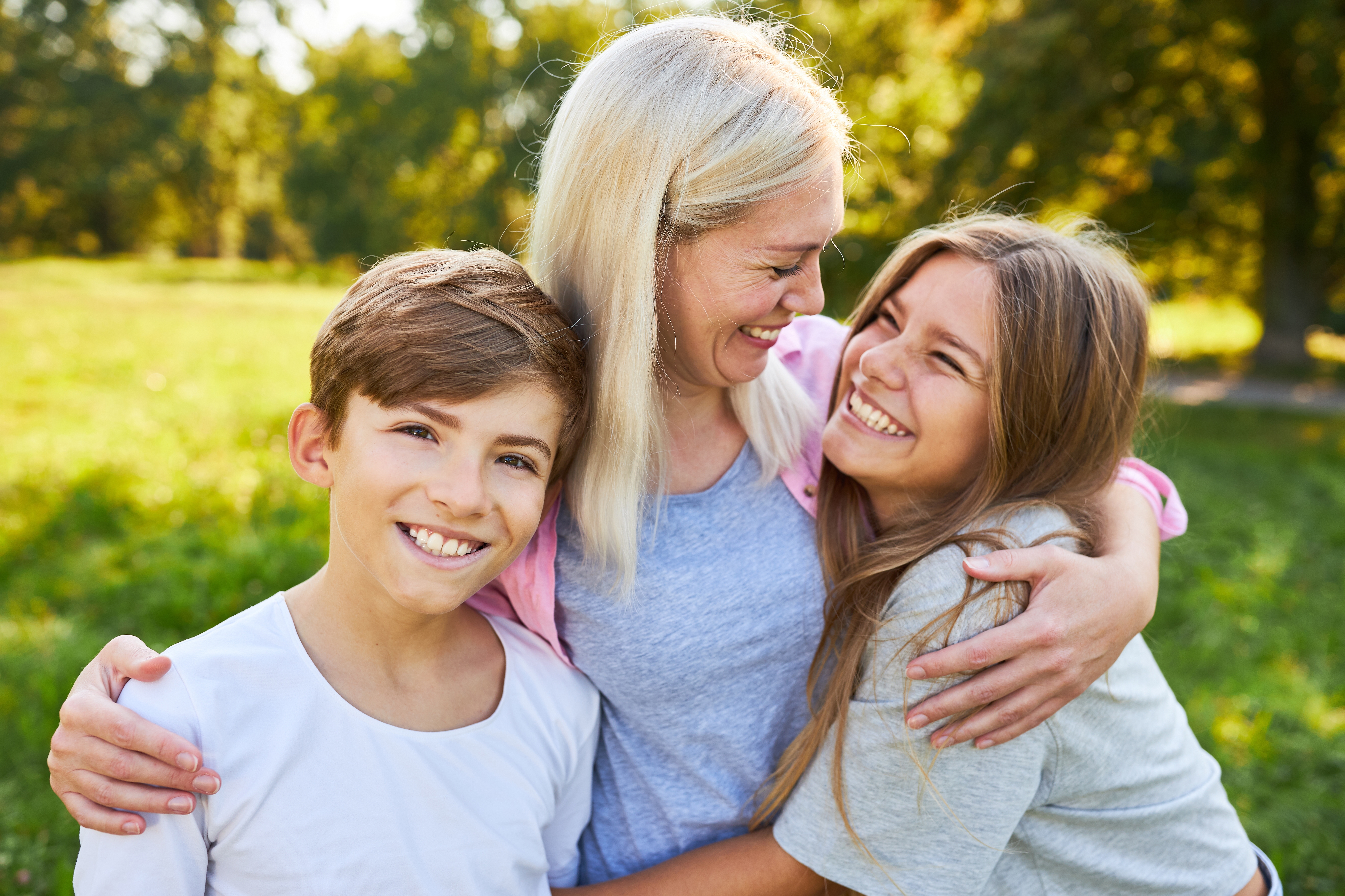 A happy mother hugging her two children outdoors | Source: Shutterstock