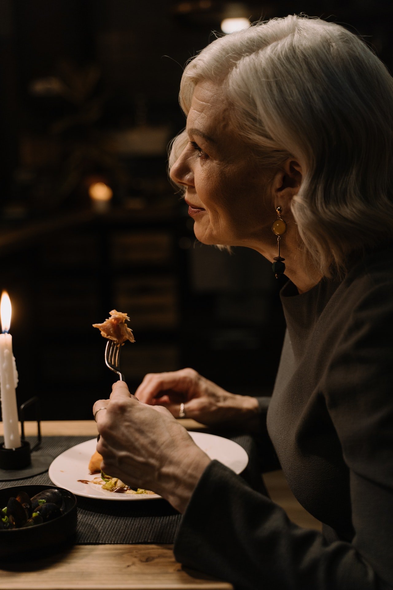 Mujer mayor sostiene el tenedor durante la comida. | Foto: Pexels