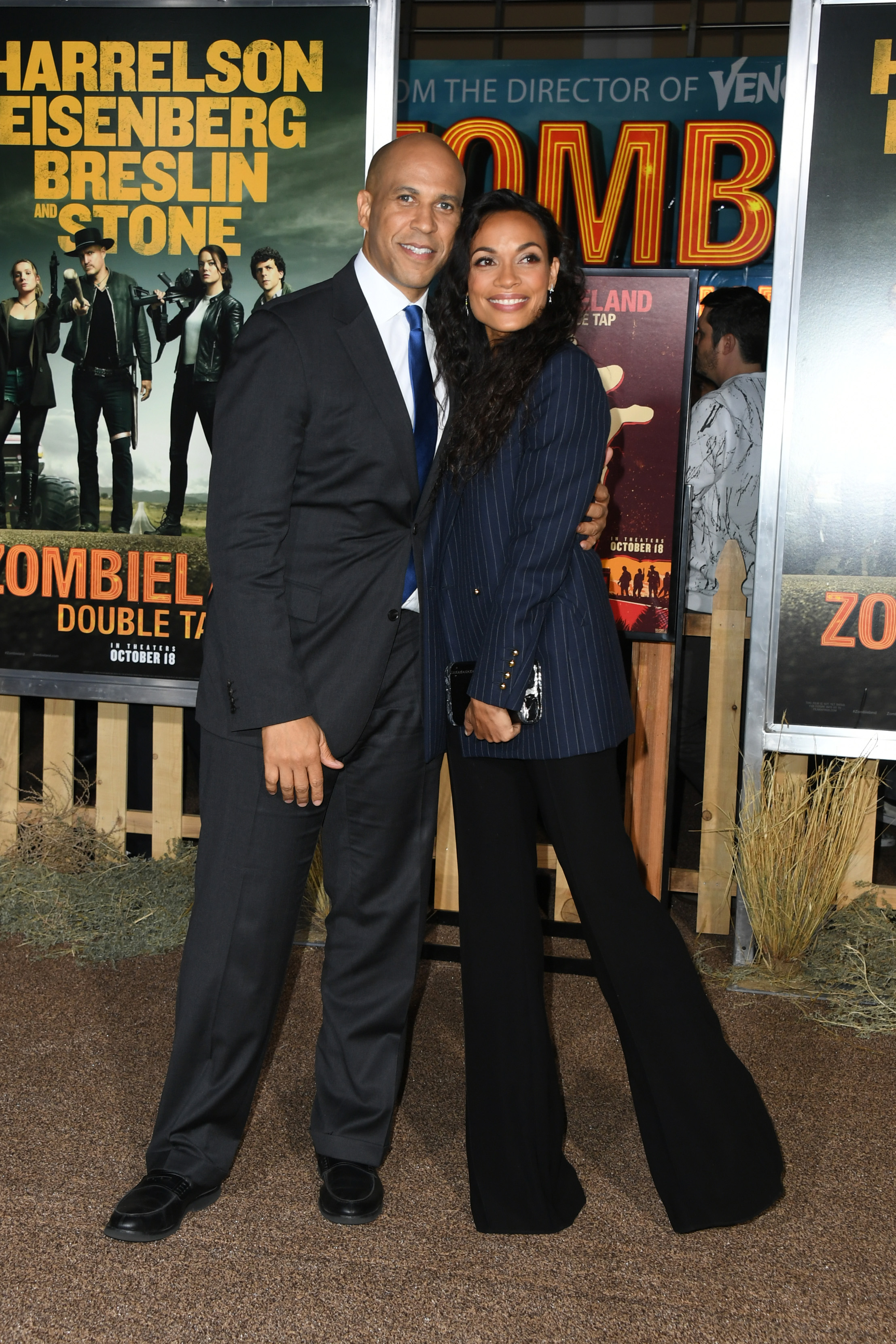 With his arm around Rosario Dawson's waist, Cory Booker faces the cameras while she beams beside him. The couple stands poised against the buzz of the Hollywood premiere backdrop.