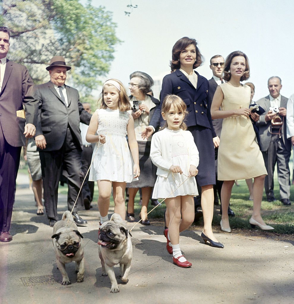 The Bouvier sisters, Jacqueline Kennedy (in blue), and Caroline Lee Radziwill (in beige), and their respective daughters, Caroline (left) and Anna walking dogs in St James' Park in London on 13th May 1965 | Source: Getty Images