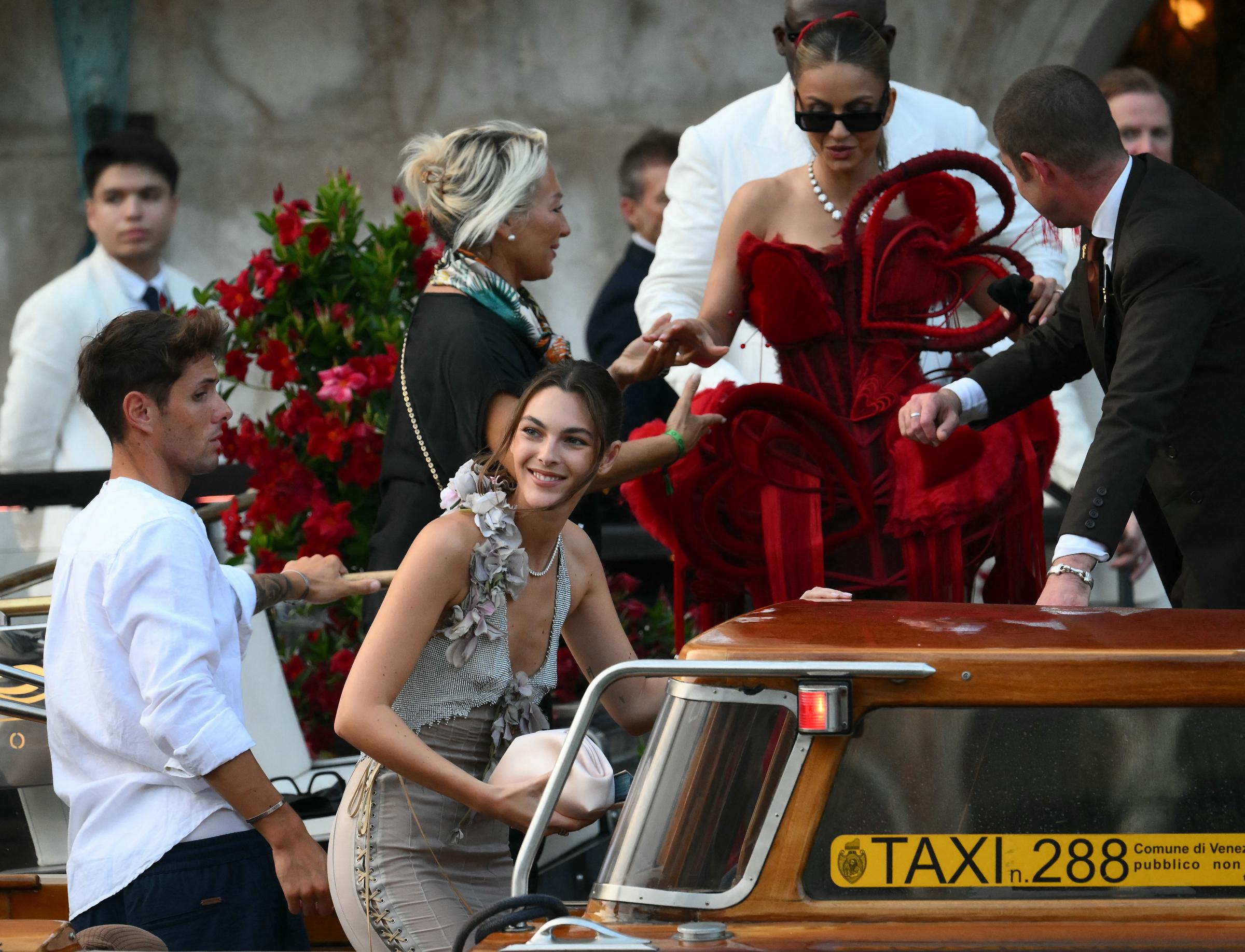 Indian philanthropist Natasha Poonawalla leaves the hotel in Venice for the highly anticipated A-list wedding. She looks radiant in her red outift fit for a queen while being assisted into the taxi boat.