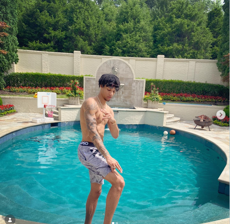 Brandon Clarke poses shirtless beside a backyard swimming pool while showing off his tattoos on a sunny day. | Source: Instagram/brandon_clarke23