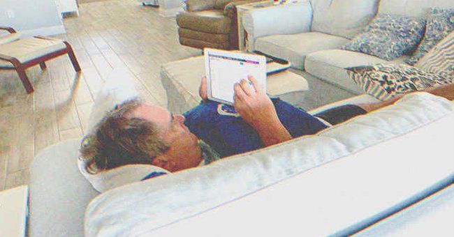 A man laying on a couch while looking at a tablet | Source: Shutterstock